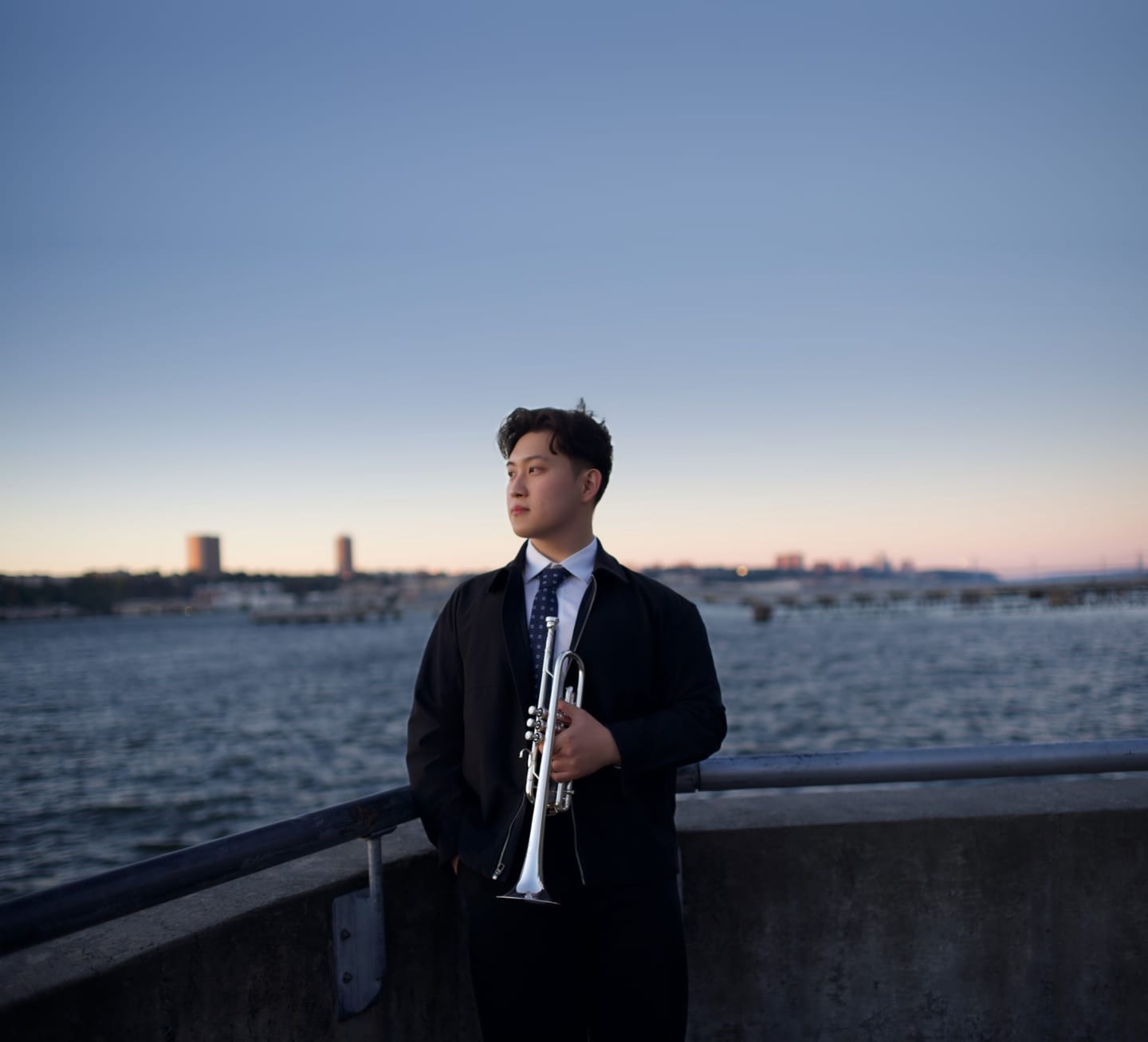 Tianyu Wang with his trumpet by the Hudson River at sunset
