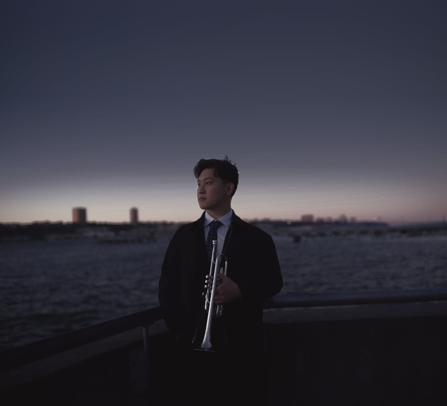 Tianyu Wang with his trumpet by the Hudson River at sunset